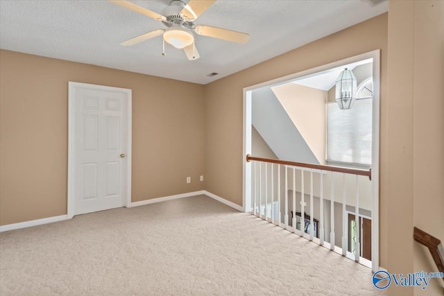 carpeted empty room with visible vents, a ceiling fan, baseboards, and a textured ceiling
