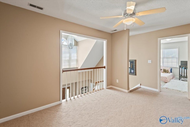 empty room featuring visible vents, a ceiling fan, a textured ceiling, carpet floors, and baseboards