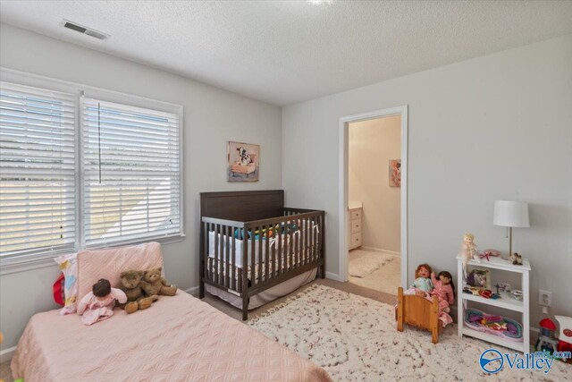 carpeted bedroom featuring baseboards, visible vents, and a textured ceiling