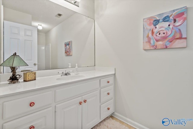 bathroom with vanity, baseboards, and visible vents