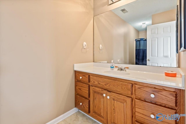 full bath featuring visible vents, baseboards, a textured ceiling, and vanity