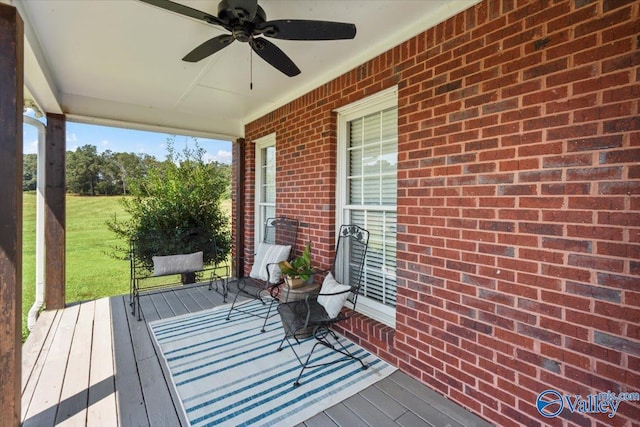 wooden terrace featuring covered porch and a ceiling fan