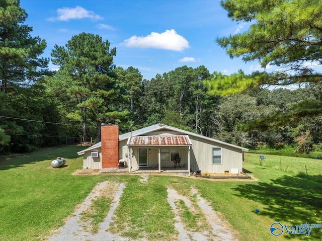 rear view of house with a lawn, a chimney, and dirt driveway