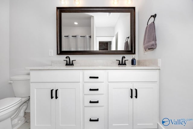 bathroom with a sink, double vanity, and toilet