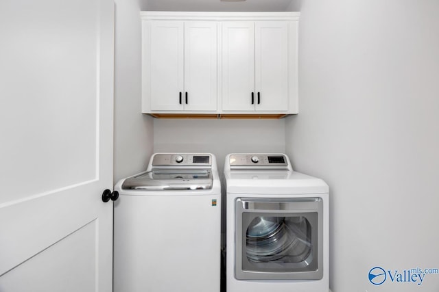 clothes washing area with independent washer and dryer and cabinet space