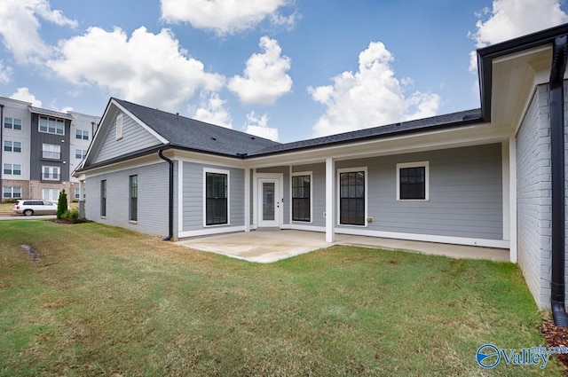 back of house featuring a patio area, brick siding, and a lawn