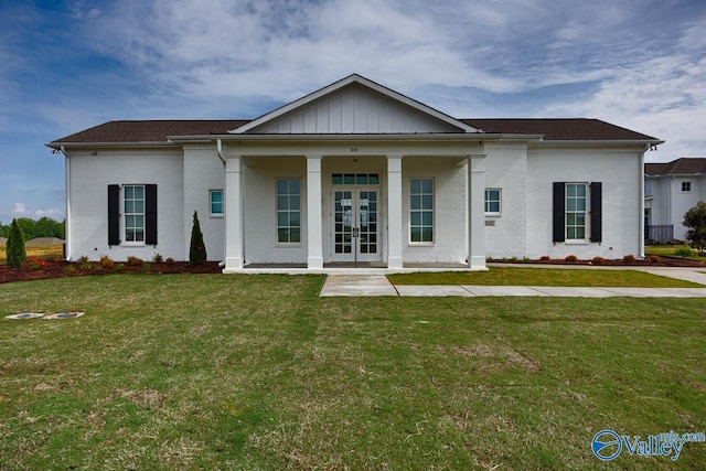 greek revival house with board and batten siding, french doors, a front yard, and brick siding