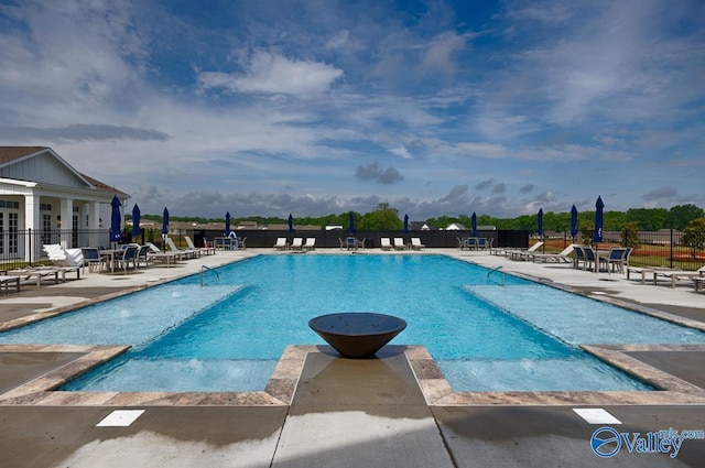 community pool with a patio area and fence