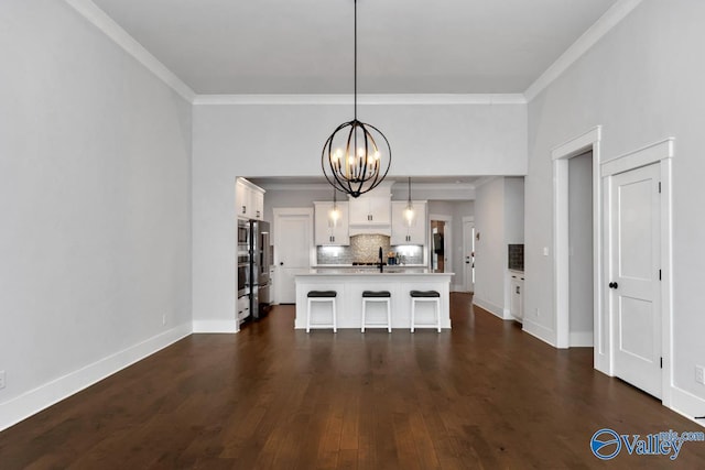 unfurnished dining area featuring dark wood-type flooring, ornamental molding, baseboards, and a chandelier