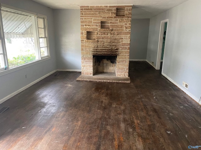 unfurnished living room with a stone fireplace and dark hardwood / wood-style floors