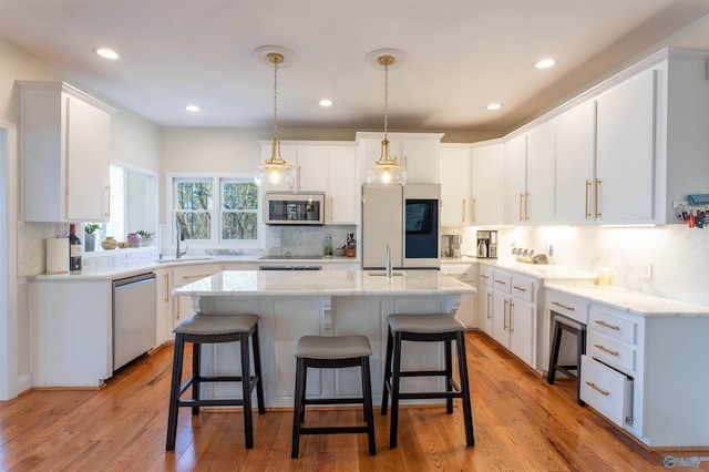 kitchen featuring white cabinetry, light wood-type flooring, stainless steel appliances, and a kitchen island