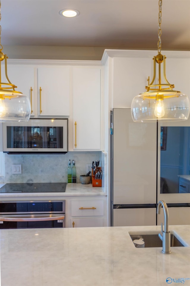 kitchen featuring decorative light fixtures, oven, decorative backsplash, sink, and white cabinets