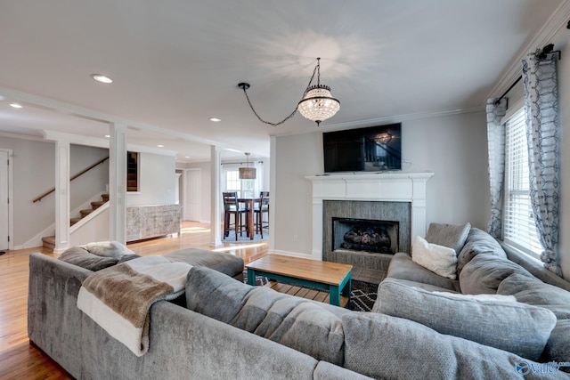 living room with a wealth of natural light, ornamental molding, and light wood-type flooring