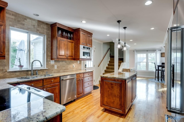 kitchen with sink, hanging light fixtures, light hardwood / wood-style flooring, a kitchen island, and appliances with stainless steel finishes