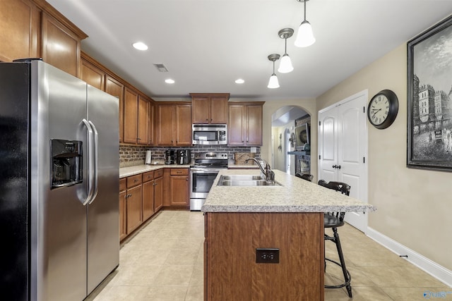 kitchen featuring tasteful backsplash, visible vents, arched walkways, a sink, and appliances with stainless steel finishes