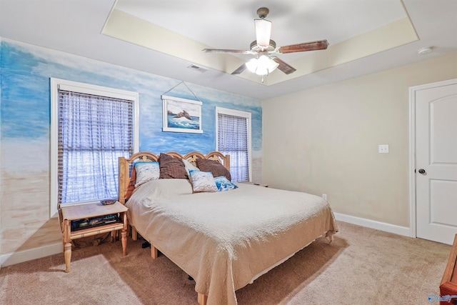 carpeted bedroom with a tray ceiling and ceiling fan