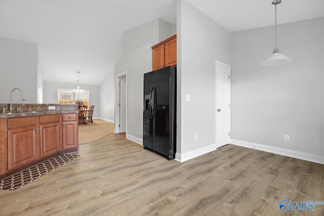 kitchen with an inviting chandelier, light wood-type flooring, sink, black fridge with ice dispenser, and decorative light fixtures