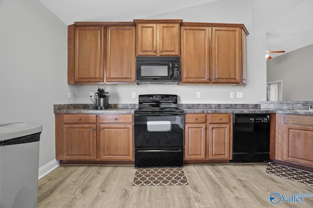 kitchen with light wood-type flooring, vaulted ceiling, and black appliances