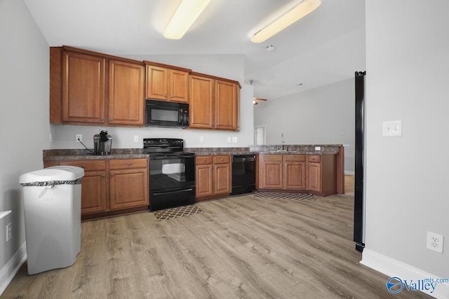 kitchen with sink, lofted ceiling, light hardwood / wood-style floors, kitchen peninsula, and black appliances