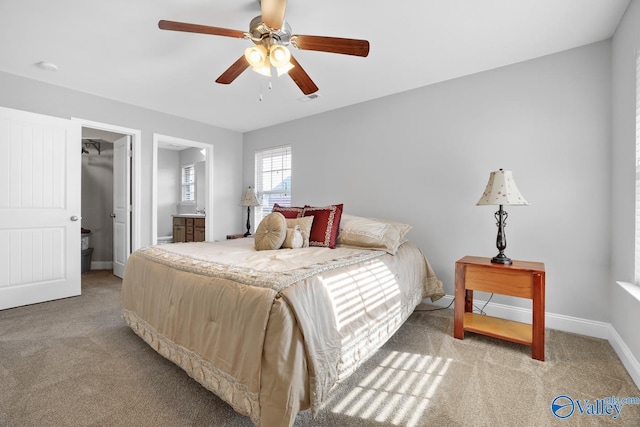 bedroom featuring a spacious closet, connected bathroom, ceiling fan, a closet, and light colored carpet