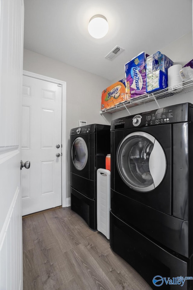 laundry area with separate washer and dryer and wood-type flooring