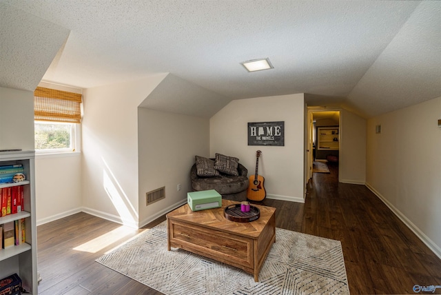 sitting room with baseboards, visible vents, dark wood finished floors, vaulted ceiling, and a textured ceiling