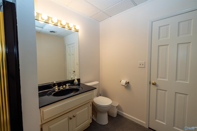 bathroom featuring baseboards, visible vents, toilet, vanity, and a paneled ceiling