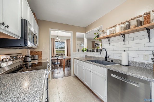 kitchen featuring a sink, open shelves, tasteful backsplash, appliances with stainless steel finishes, and white cabinets