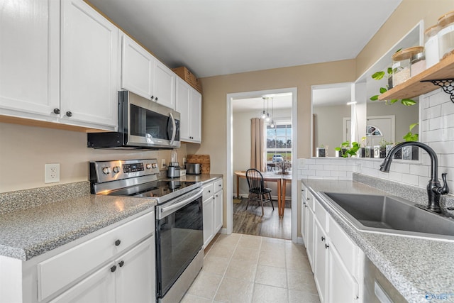 kitchen with light countertops, a sink, white cabinetry, stainless steel appliances, and decorative backsplash