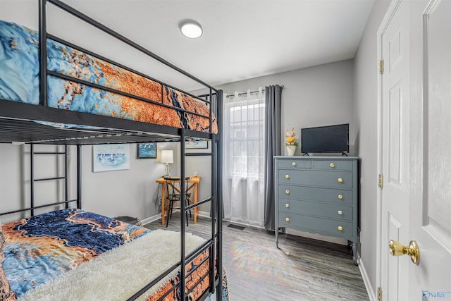 bedroom with visible vents, baseboards, and wood finished floors