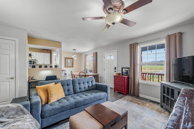 living room with baseboards, wood finished floors, a healthy amount of sunlight, and a ceiling fan
