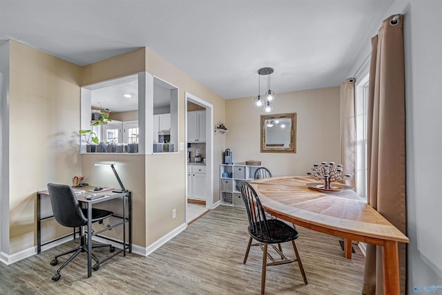 dining area featuring light wood finished floors and baseboards