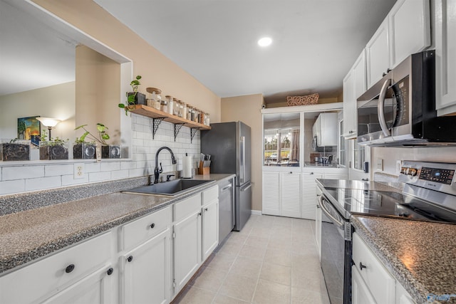 kitchen featuring decorative backsplash, white cabinets, stainless steel appliances, a sink, and open shelves
