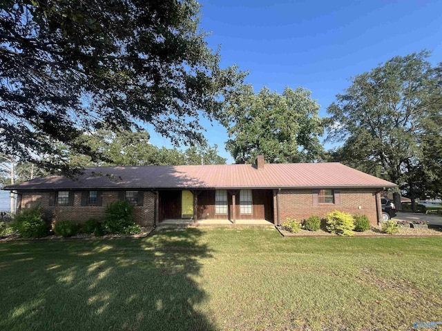 ranch-style home featuring a front yard, brick siding, and a chimney