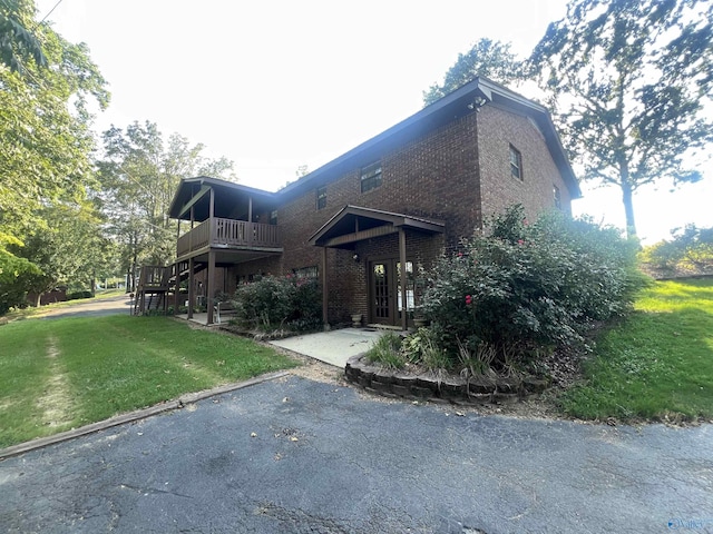 view of front of house with a patio area, a front yard, stairway, and brick siding