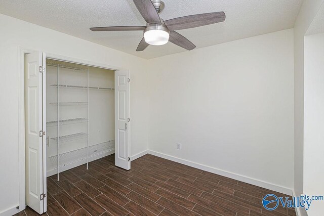 unfurnished bedroom with ceiling fan, dark hardwood / wood-style flooring, a closet, and a textured ceiling