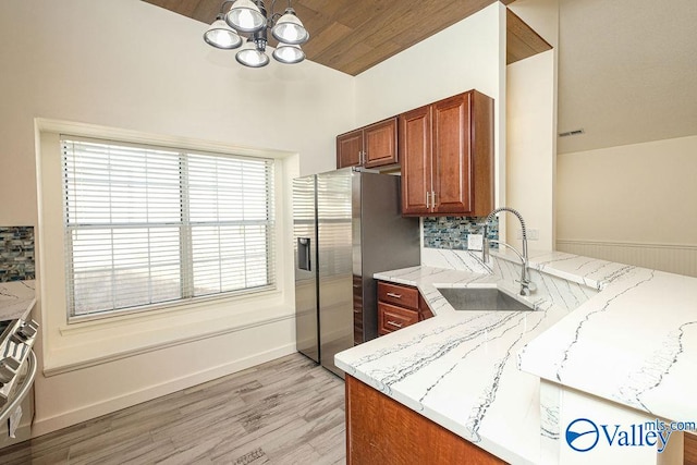 kitchen with sink, decorative backsplash, light stone countertops, and a chandelier