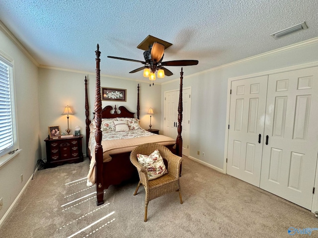 bedroom with a textured ceiling, carpet flooring, ceiling fan, and ornamental molding