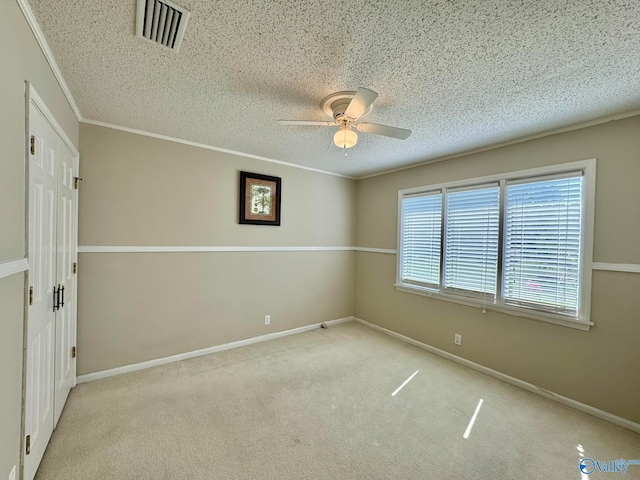 carpeted spare room with ornamental molding, a textured ceiling, and ceiling fan