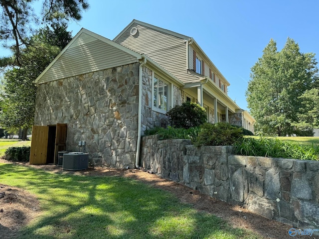 view of side of home with a yard and central AC unit