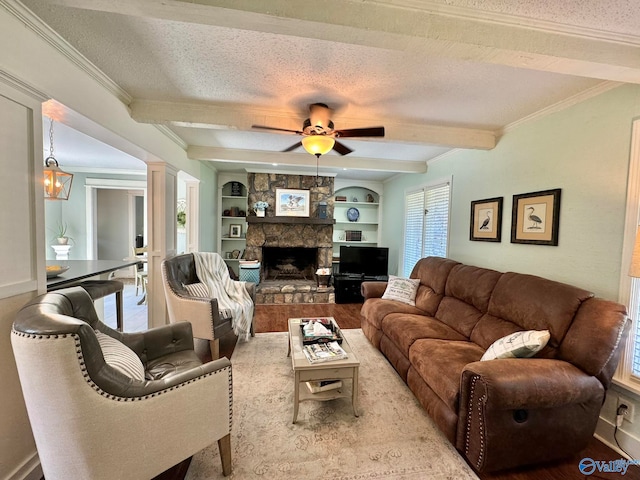 living room with a stone fireplace, built in shelves, ceiling fan, and a textured ceiling