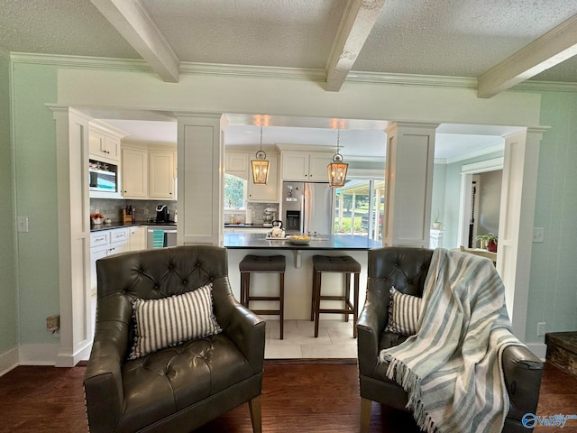 living area featuring a textured ceiling, beamed ceiling, hardwood / wood-style flooring, and decorative columns