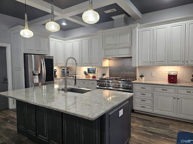 kitchen featuring stainless steel appliances, beam ceiling, and a center island with sink