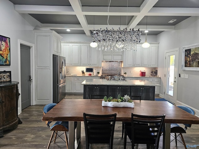 kitchen featuring stainless steel fridge, decorative light fixtures, a kitchen island with sink, and white cabinets