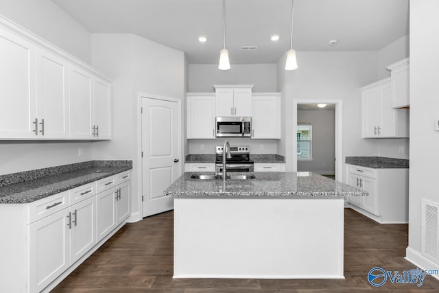 kitchen featuring stainless steel appliances, a sink, a kitchen island with sink, and white cabinets