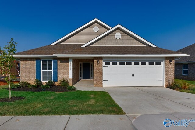 view of front of home featuring brick siding, roof with shingles, a garage, driveway, and a front lawn