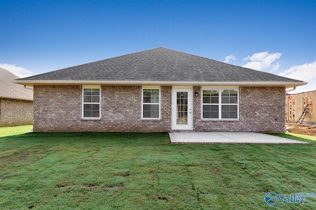 back of house with a yard, brick siding, roof with shingles, and a patio area