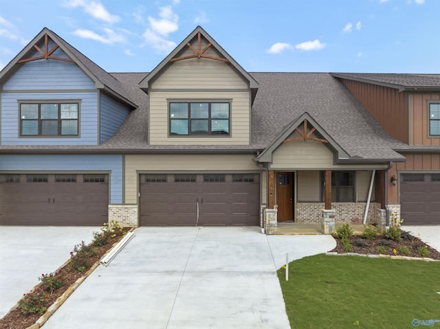 craftsman house with driveway, board and batten siding, a shingled roof, a garage, and brick siding