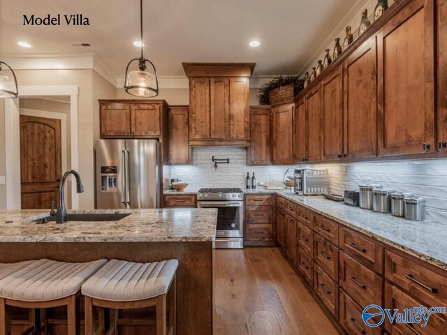 kitchen with premium appliances, tasteful backsplash, light stone countertops, wood-type flooring, and sink