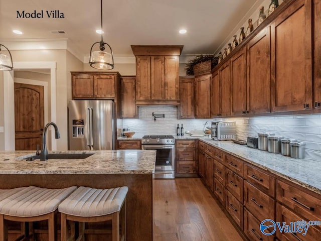 kitchen with brown cabinets, a sink, tasteful backsplash, dark wood-style floors, and appliances with stainless steel finishes